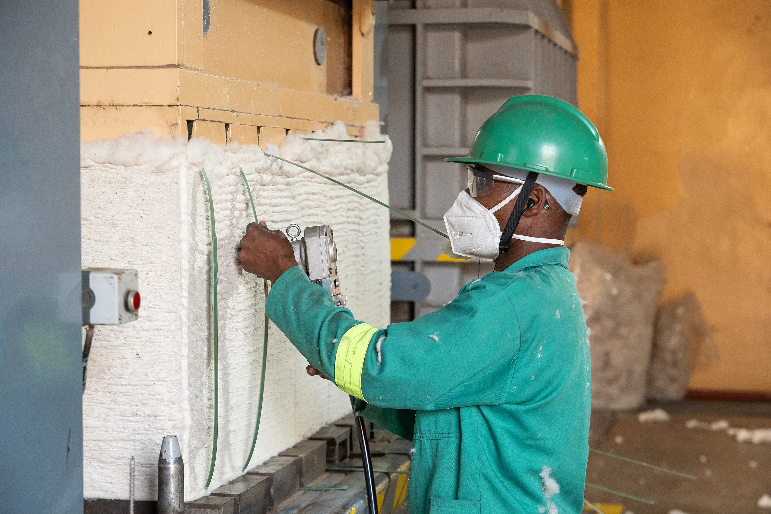 A technician in protective gear at a plant wall