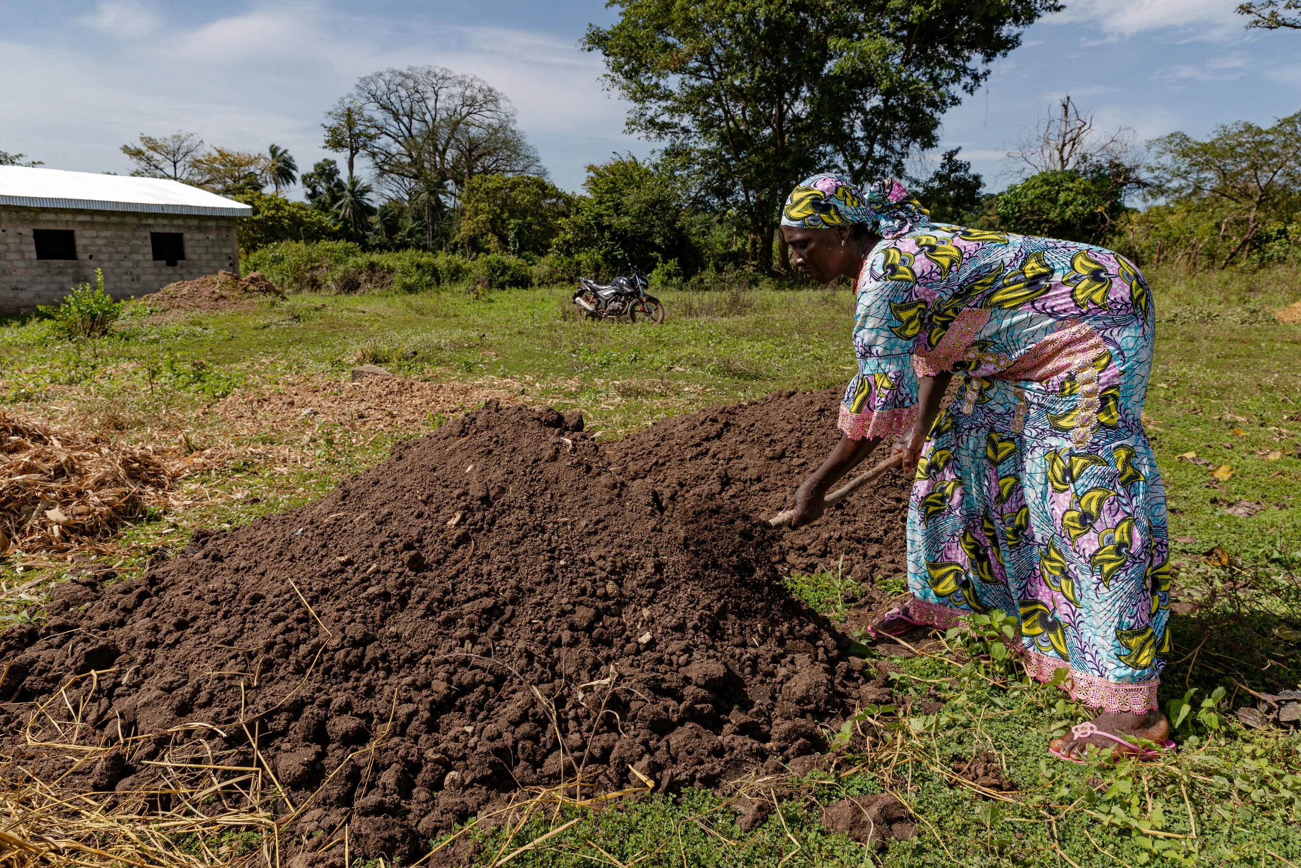 A woman spreading a heap of dark soil with her hands