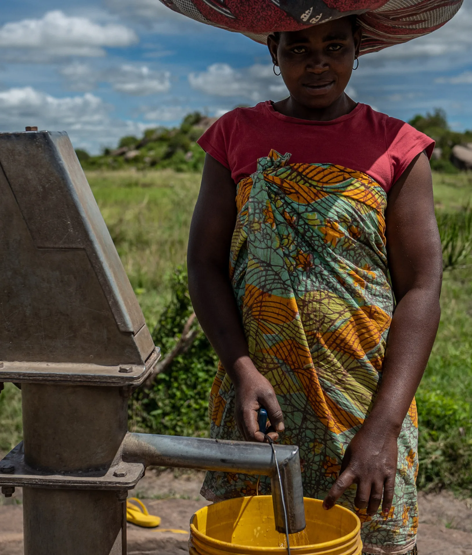 A woman fetching water at a hand pump