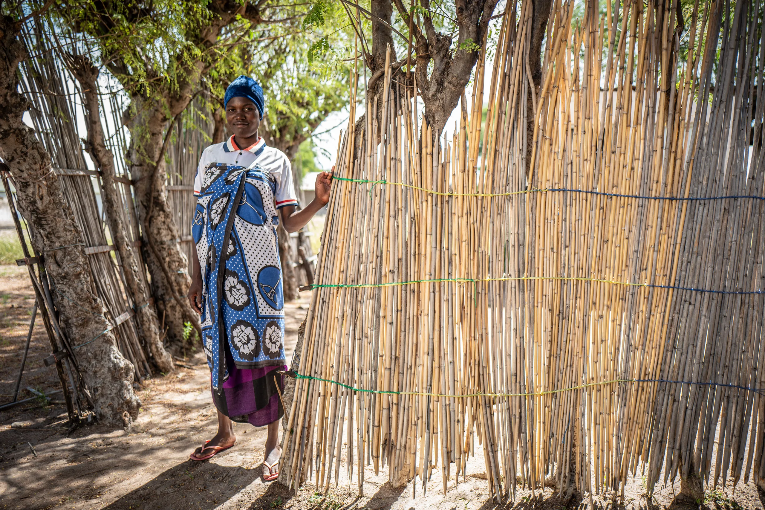 A woman standing beside a bamboo fence