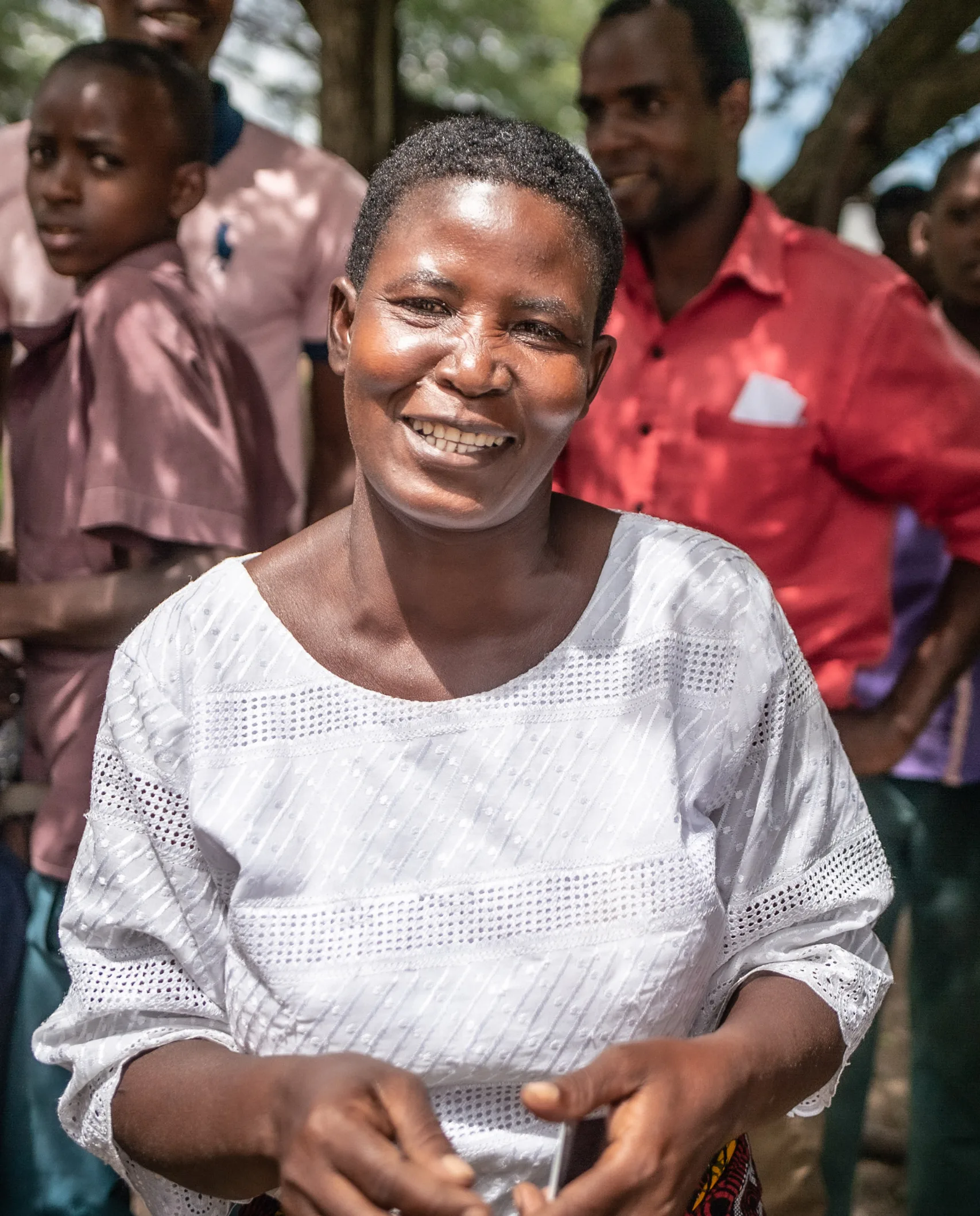 A smiling woman among a group under a tree